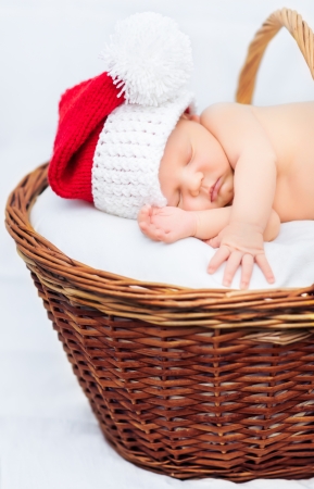 Cute newborn baby wearing Santa Claus hat sleeping in basket, Christmas, New Yearの写真素材