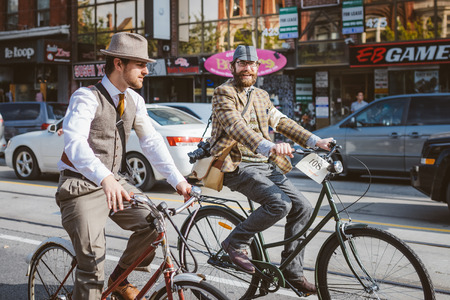 Toronto, Canada - September 20, 2014: Unidentified participants of Tweed Ride Toronto in vintage style clothes riding on their bicycles. This event is dedicated to the style of old Englandのeditorial素材