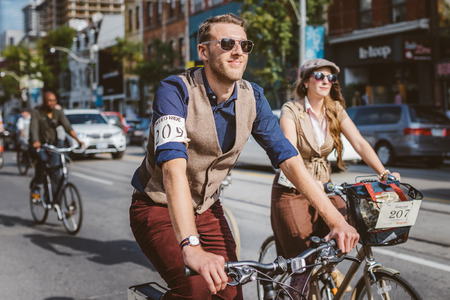 Toronto, Canada - September 20, 2014: Unidentified participants of Tweed Ride Toronto in vintage style clothes riding on their bicycles. This event is dedicated to the style of old Englandのeditorial素材