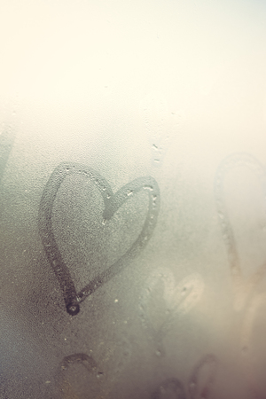 Closeup on drawing love hearts on wet window backgroundの写真素材