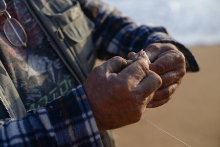 Hand holding a fish caught on a fishing line in lake.の写真素材