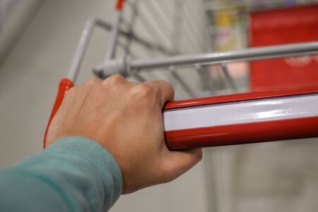 Closeup on hand with shopping cart. Buyer in supermarketの写真素材