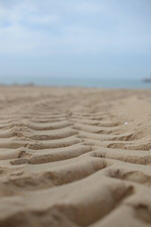 Closeup on ribbed tire traces on dry sand of ocean beach. traveling, transport and ecologyの写真素材