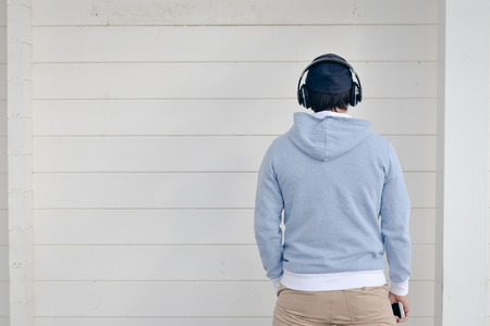 Back view of a man listening music with headphones, on white background wallの写真素材