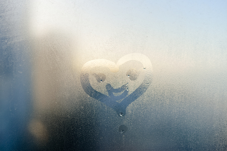 Smile face and heart drawing on window, season abstract background. Rain dropsの写真素材