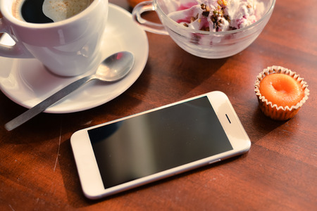Top view of coffee cup, smart phone, icecream and cakes on wood background. Flat lay style.の写真素材
