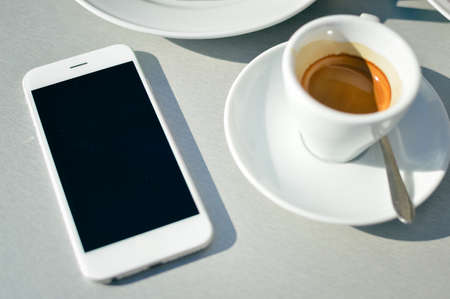 Top view of coffee cup and mobile phone on table background, closeupの写真素材
