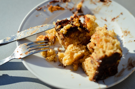 Closeup on dirty dish with cake on light table, top view