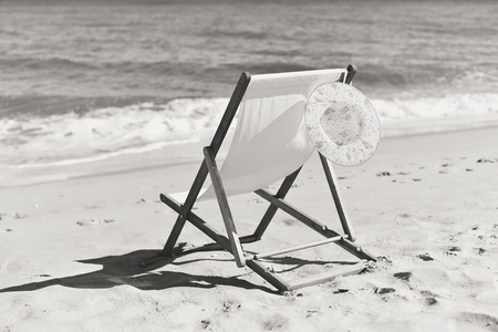Black and white picture of female hat and deckchair on the beach vacation, sunny outdoors backgroundの写真素材