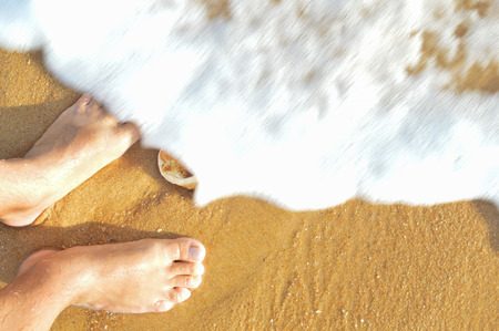 Beach outdoors background - feet and sea shell. Summer vacation ideaの写真素材