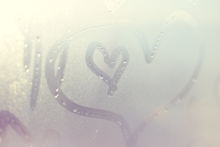 Closeup on drawing heart on wet window backgroundの写真素材