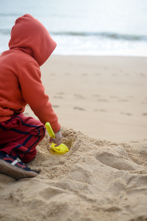 Child playing on the beach with sand shovelの写真素材