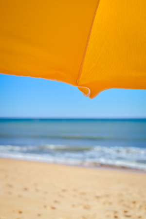 Holiday view of sun umbrella, sandy beach and ocean shore background outdoorsの写真素材
