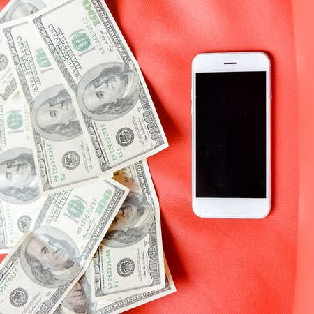 Top view of cell phone, money bills on red background. Flat lay style closeup, black copy spaceの写真素材