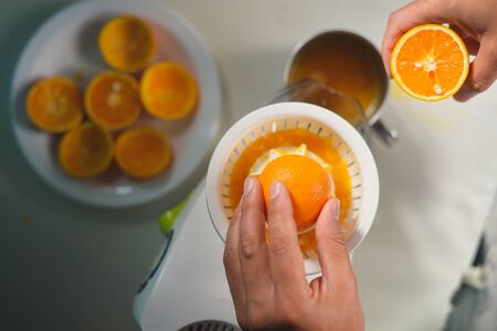 Hand holding orange fruit and making fresh drinkの写真素材