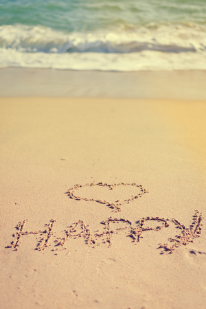 Love heart and happy word, honeymoon or valentine's day greetings on the sandの写真素材