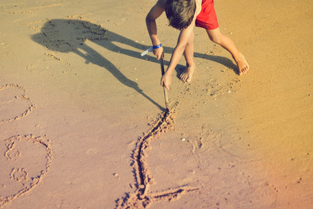 Top view on little boy drawing on sand beach, vacation relaxationの写真素材