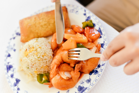 Oriental rice with sea food and hands hold fork knife close up photo