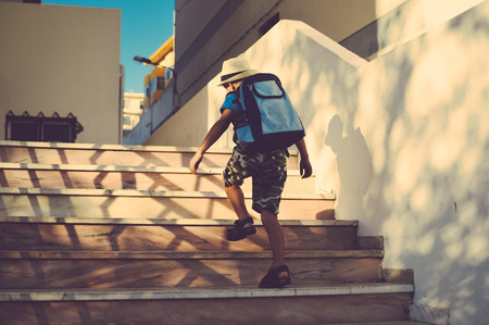 Back view of boy walking on stairs outdoors building backgroundの写真素材