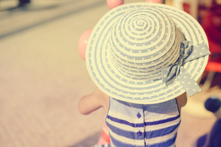Back view of little baby girl walking on a sunny road outdoors backgroundの写真素材