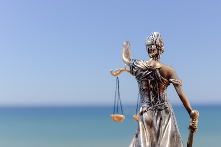 Back view of Justice Themis goddess sculpture on bright sky copy space background.の写真素材