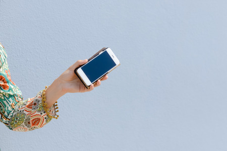 Closeup on smartphone in the hand with blue sky on the background