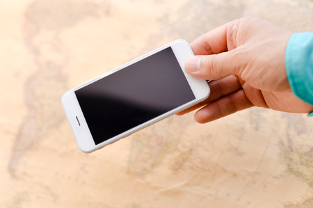 Closeup on business man hand showing smartphone with world map for social and internet projects. Gps navigation searching mockup technologyの写真素材