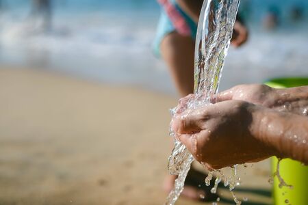 Hand and water, wet sand blurry outdoors background, close up imageの写真素材