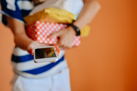 Mock up view woman smart phone, carrying present box, copy space background. Close up hand hold touch screen telephoneの写真素材