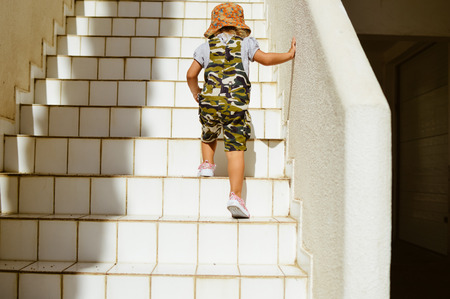 Child climb up staircase background. Back view imageの写真素材