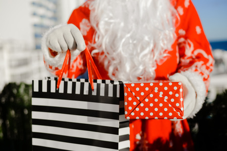Merry Christmas with joyful Santa Claus ready to ship and delivering gift packages on sunny blue sky outdoors background. Happy time for amazement and excitementの写真素材