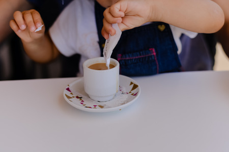 Closeup on hands pouring sugar on coffee cup.の写真素材