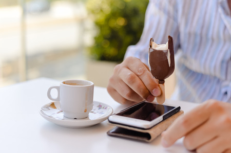 Closeup on person sitting in cafe having ice cream and coffee, working on mobile phone. Mockup top...