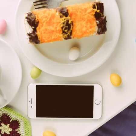Algarve, Portugal - May 5, 2016: Top view of iPhone 6 smartphone, coffee cup and cakes on table...