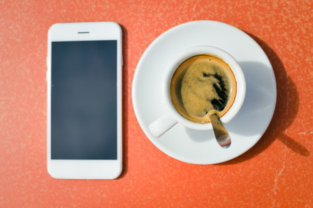 Closeup on coffee cup phone screen, top view flat lay table backgroundの写真素材