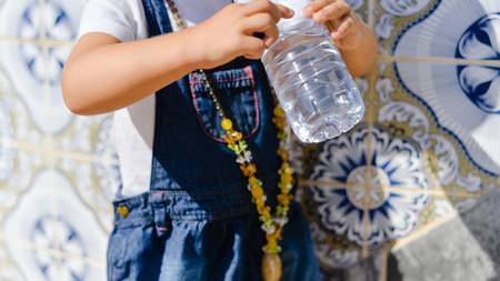 Closeup view of little child drinking water, hands holding bottleの写真素材