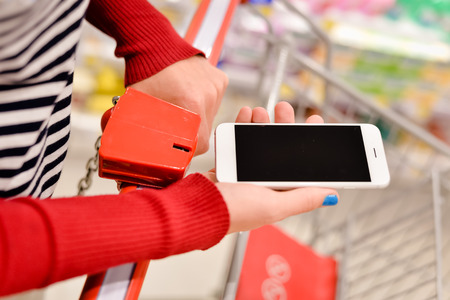 Closeup on smart phone online shopping in woman hand. Shopping center in background.の写真素材