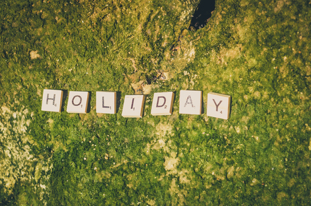 Top view on "Holiday" wooden sign pazzle abstract design on the beach backgroundの写真素材