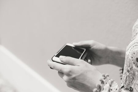 Female hand holding cell phone, mock up background. Black and white close up viewの写真素材