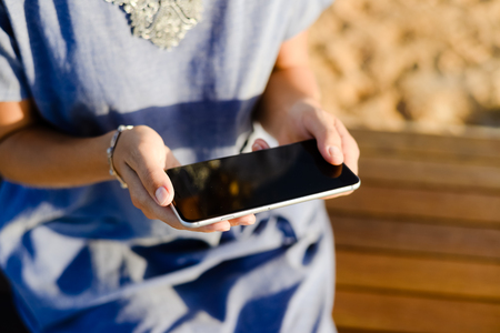 Hands of woman using cellphone with blank screen backgroundの写真素材