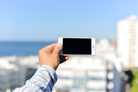 Closeup on smartphone in the hand with blue sky on the backgroundの写真素材