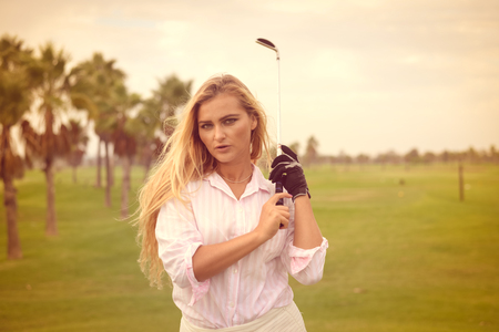 Portrait of beautiful woman relaxing during playing golf on a green field outdoors backgroundの写真素材