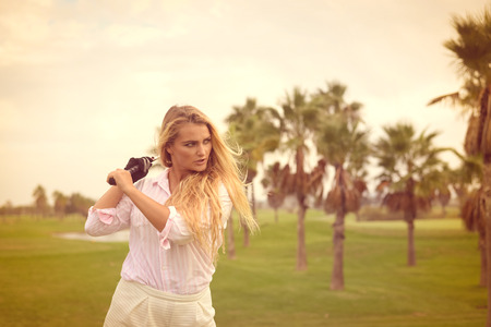 Portrait of beautiful woman relaxing during playing golf on a green field outdoors backgroundの写真素材