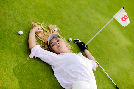 Portrait of beautiful woman relaxing during playing golf on a green field outdoors backgroundの写真素材