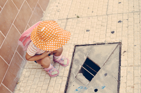 Child looking at hole in pavement, ground outdoors background. Top viewの写真素材