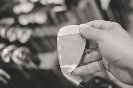 Black and white shot of choosing holding golf club in hand, close up view, defocused backgroundの写真素材