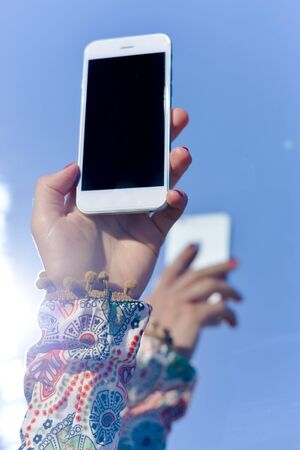 Hands of woman using cellphone with blank screen background
