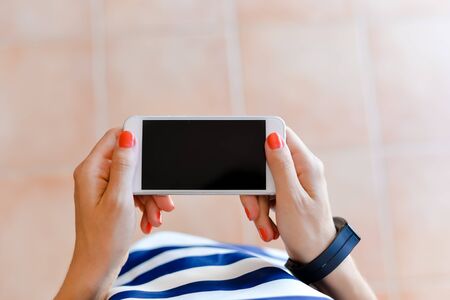 Female holding using a smartphone and shopping box. Top view closeup
