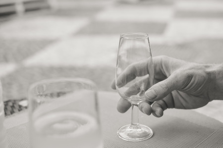 Closeup view of male hand holding a wine glass, table backgroundの写真素材