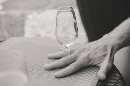 Closeup view of male hand holding a wine glass, table backgroundの写真素材